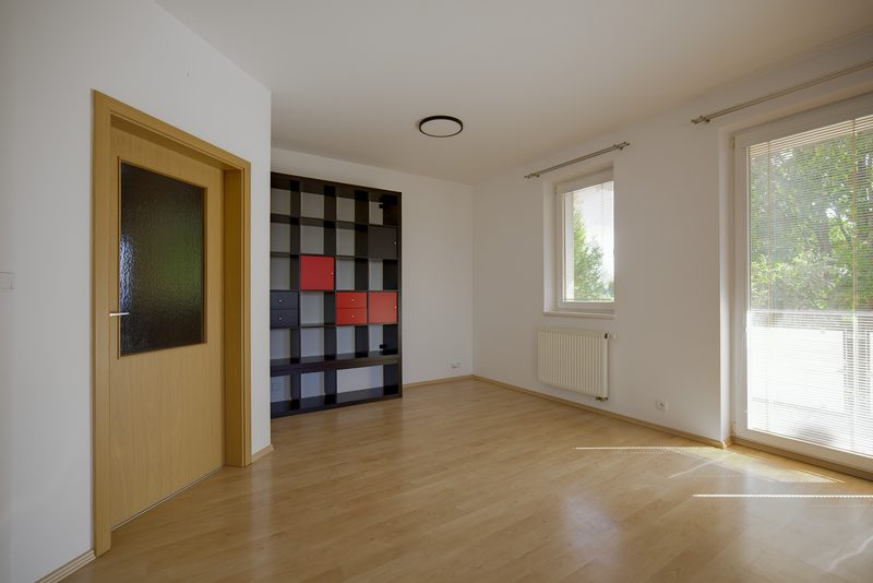 Kout obýváku s regálem a balkónovými dveřmi