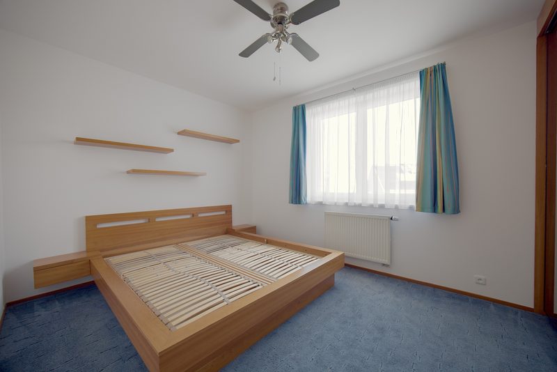 Ložnice s postelí a stropním ventilátorem