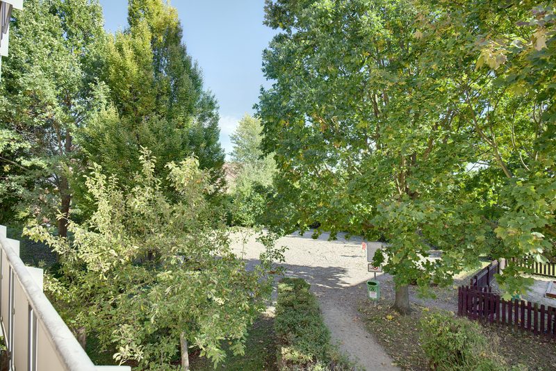 Výhled z balkónu do vnitrobloku se stromy